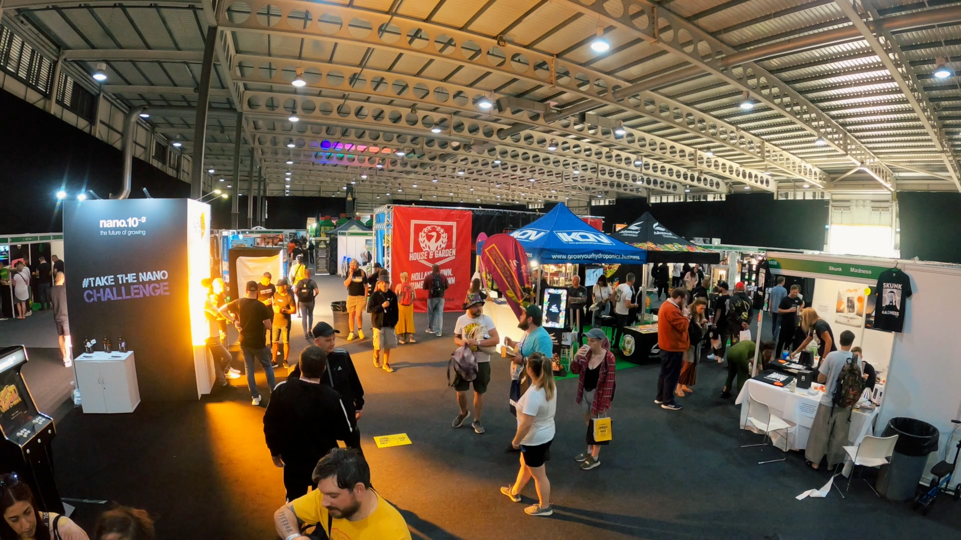 The interior of a busy expo hall with a range of people walking around stalls.