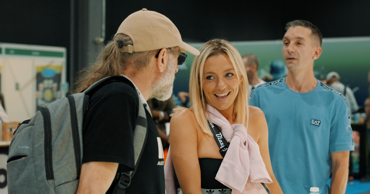 A man in a beige hat and a woman with a pink scarf smiling at an expo event