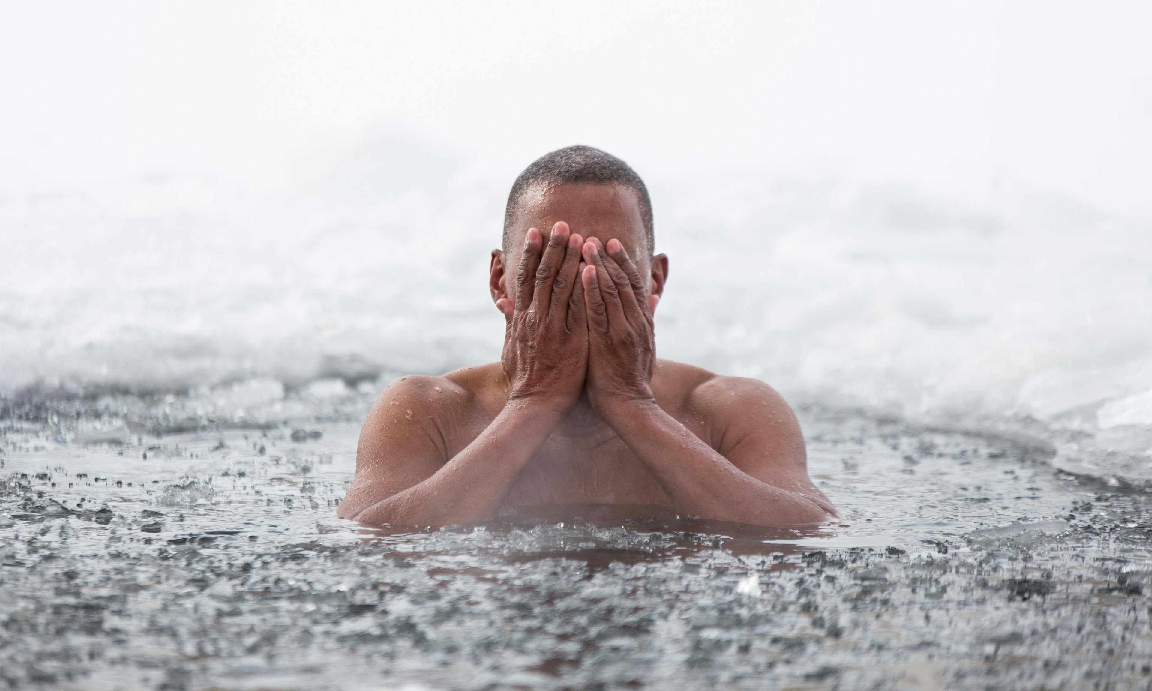 Man in an ice lake covering his face with his hands